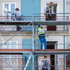 Trabajadores en andamios renuevan fachadas de edificios, cumpliendo la normativa sobre estética fachadas de edificios.