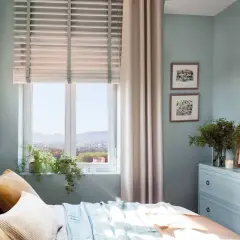 Acogedor plano dormitorio 9 metros cuadrados con cama, cómoda azul, cuadros y vistas a la ciudad.