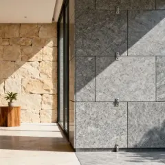 Un sofá beige junto a una pared de piedra dorada y una pared moderna de **mármol material** gris con sombras marcadas.