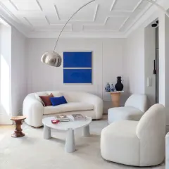 Sofá blanco y sillones acogedores, mesa de centro de mármol y arte abstracto azul. Ideas para decorar paredes salón.