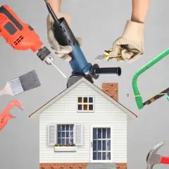 Manos con guantes sostienen herramientas de construcción alrededor de una casa. ¡Calcula tu reforma casa precio!