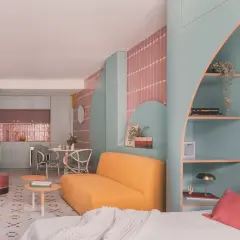Habitación de 4 metros cuadrados con sofá amarillo, estanterías turquesas y detalles en rosa. Cocina y comedor integrados.