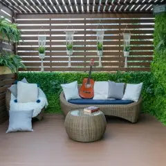 Un rincón acogedor para cerrar el patio exterior, con sofá, sillón, mesa y guitarra.