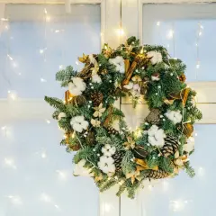 Corona de Adviento con piñas, algodón y canela, ideal para decorar una ventana de Navidad. Luces cálidas la iluminan.