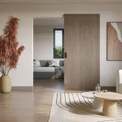 Instalar puerta corredera de madera en un salón moderno. Un jarrón con pampas secas decora el espacio.