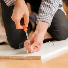 Man at work, using a screwdriver to unir tablero.
