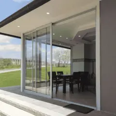 Techar un patio sin perder luz es posible con este diseño de cristal. El interior, con mesa y sillas, se integra al jardín.