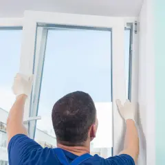 Un técnico con guantes blancos ajusta un marco para cambiar ventanas.