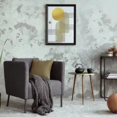 Salón moderno con pared texturizada que combina papel pintado y pintura. Sillón gris, mesa auxiliar dorada y arte abstracto.