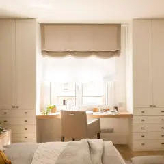 Escritorio funcional para aprovechar espacio bajo ventana, con armarios a ambos lados.