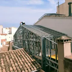 Un trabajador instala un tejado de steel framing sobre un edificio.