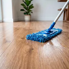 Un trapeador azul limpia un suelo de madera brillante. Aprende como limpiar suelo de madera para mantenerlo reluciente.