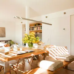 Un espacio luminoso y moderno para diseñar salón, con mesa de madera, sofás cómodos y estanterías llenas de libros.
