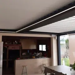 Un moderno patio de luces con normativa de iluminación LED integrada, que ilumina una cocina exterior y zona de comedor.