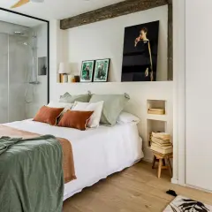 Dormitorio con ducha integrada, cama con mantas cálidas y cuadros. Una reforma sin obras que transforma el espacio con estilo y funcionalidad.