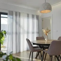 Comedor moderno con mesa y sillas, y diferentes tipos de cortinas que filtran la luz.