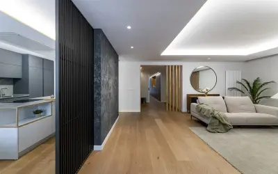 Cocina moderna y salón con sofá beige. El suelo de madera y la decoración crean un ambiente acogedor. Ideal para calcular el precio reforma integral.
