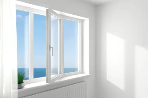 Ventana oscilobatiente de 2 hojas abierta, dejando entrar la brisa marina y la luz del sol.