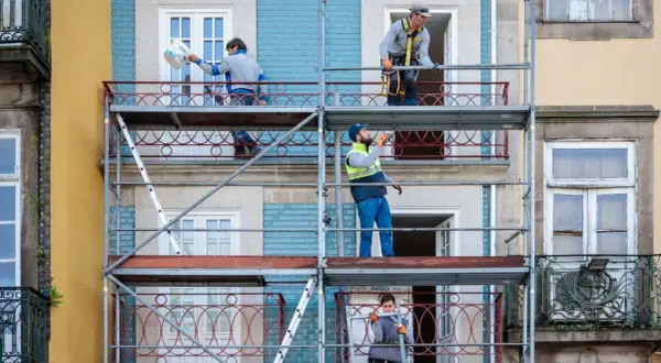 Trabajadores en andamios renuevan fachadas de edificios, cumpliendo la normativa sobre estética fachadas de edificios.