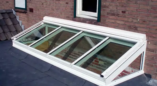 Monteras para patios, un tragaluz moderno de vidrio y aluminio sobre un tejado, ilumina el interior con luz natural.