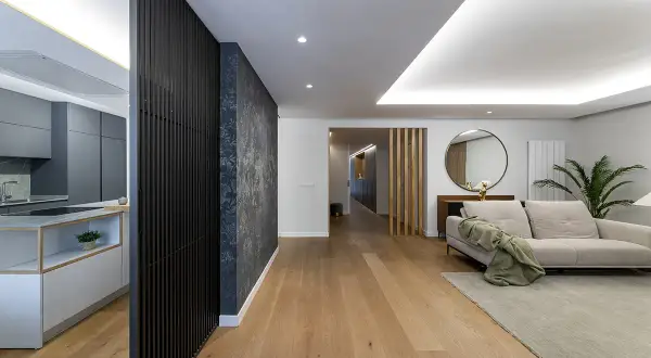 Cocina moderna y salón con sofá beige. El suelo de madera y la decoración crean un ambiente acogedor. Ideal para calcular el precio reforma integral.