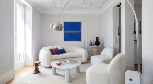 Sofá blanco y sillones acogedores, mesa de centro de mármol y arte abstracto azul. Ideas para decorar paredes salón.