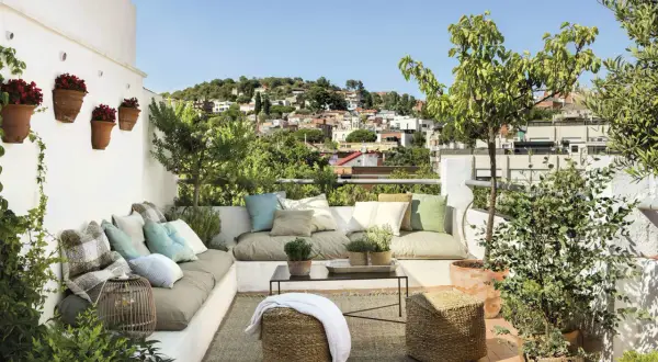 Un rincón perfecto para **chill out** en la **terraza**, con cómodos cojines, plantas y vistas a la ciudad.
