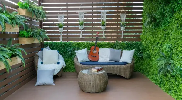 Un rincón acogedor para cerrar el patio exterior, con sofá, sillón, mesa y guitarra.