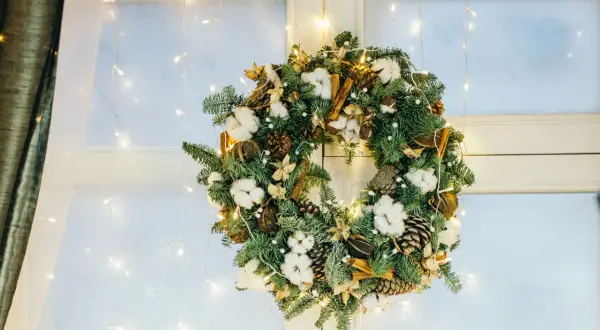 Corona de Adviento con piñas, algodón y canela, ideal para decorar una ventana de Navidad. Luces cálidas la iluminan.