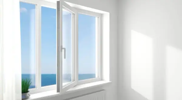Ventana oscilobatiente de 2 hojas abierta, dejando entrar la brisa marina y la luz del sol.