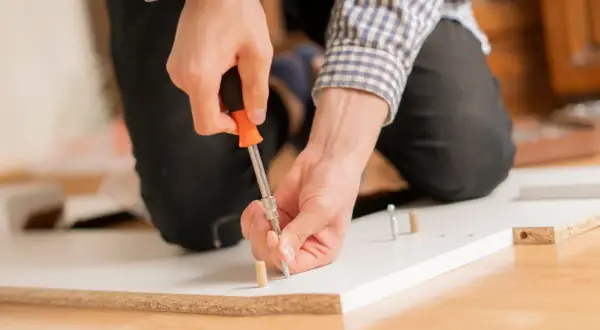 Man at work, using a screwdriver to unir tablero.