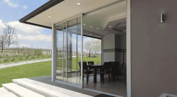 Techar un patio sin perder luz es posible con este diseño de cristal. El interior, con mesa y sillas, se integra al jardín.