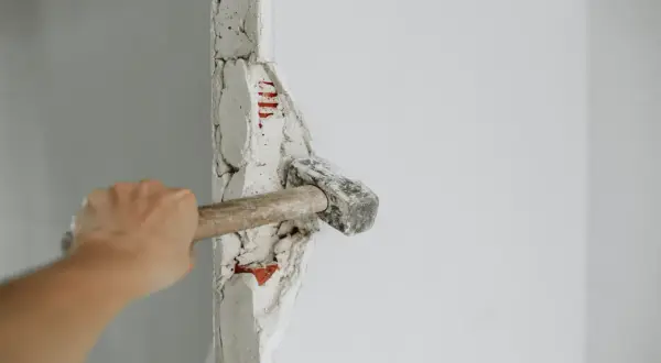 Mano golpeando un tabique con un mazo. ¡Demostrando que puedo tirar un tabique yo mismo!