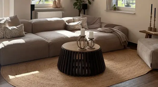 Alfombra redonda de yute, uno de los tipos de alfombras más naturales y versátiles, complementa un salón moderno con sofá modular y mesa de centro.