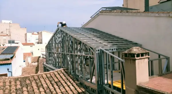 Un trabajador instala un tejado de steel framing sobre un edificio.
