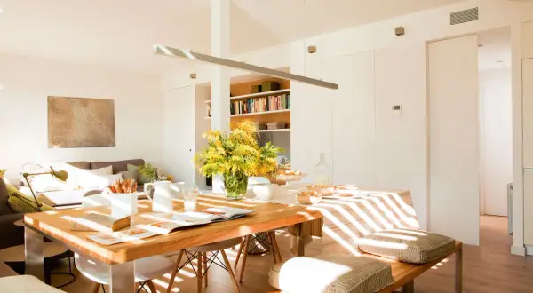Un espacio luminoso y moderno para diseñar salón, con mesa de madera, sofás cómodos y estanterías llenas de libros.
