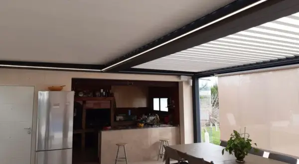 Un moderno patio de luces con normativa de iluminación LED integrada, que ilumina una cocina exterior y zona de comedor.