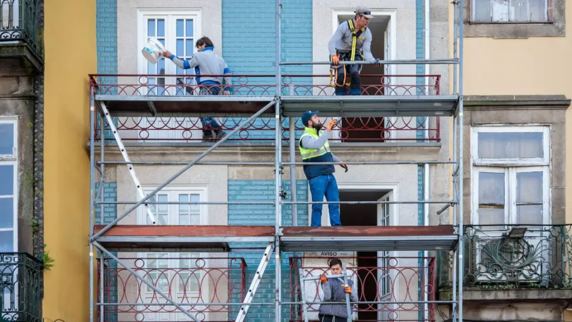 Trabajadores en andamios renuevan fachadas de edificios, cumpliendo la normativa sobre estética fachadas de edificios.