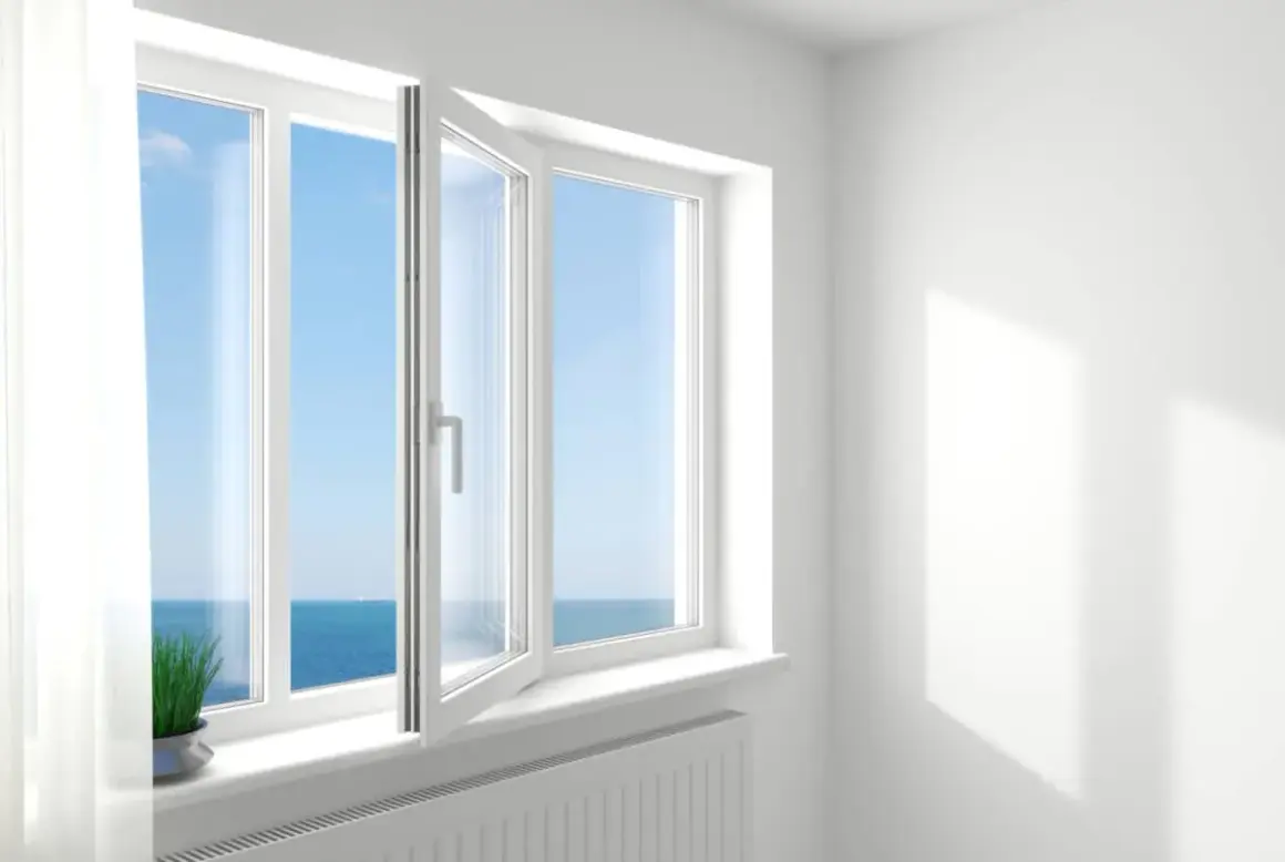 Ventana oscilobatiente de 2 hojas abierta, dejando entrar la brisa marina y la luz del sol.