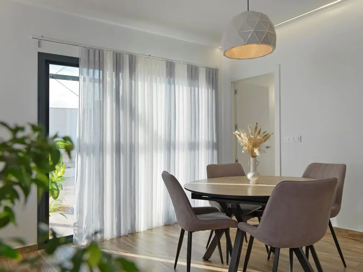 Comedor moderno con mesa y sillas, y diferentes tipos de cortinas que filtran la luz.