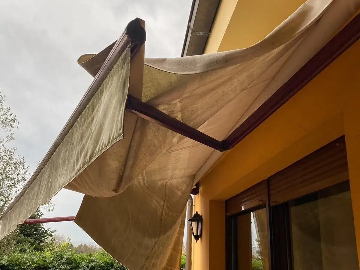 Toldo desgastado en terraza, quiz&aacute;s incumpliendo la normativa toldos en terrazas. Se ve la estructura y la tela beige.
