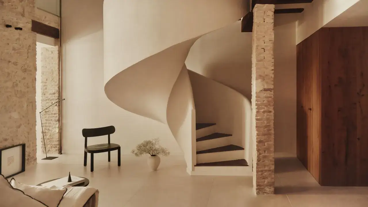 Elegante vivienda antigua con escalera de caracol moderna, paredes de ladrillo expuesto y armarios de madera.