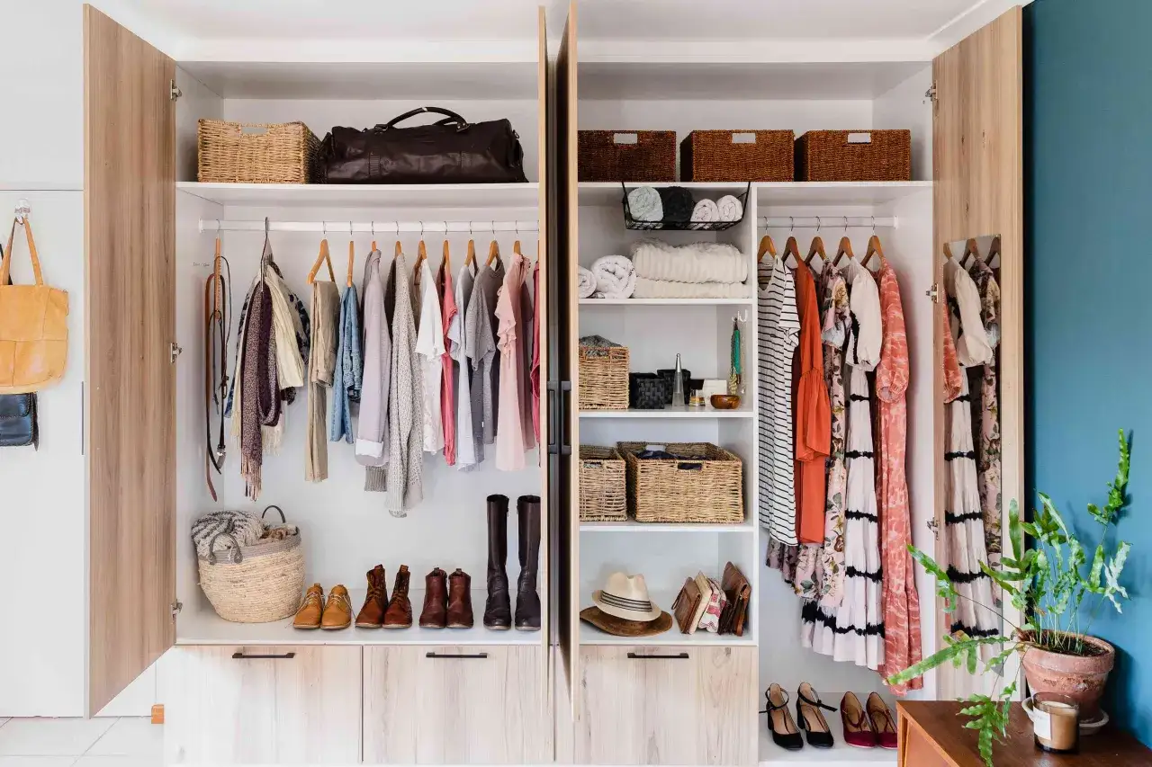 Armarios organizados con ropa colgada, cestas de mimbre, bolsos y zapatos.