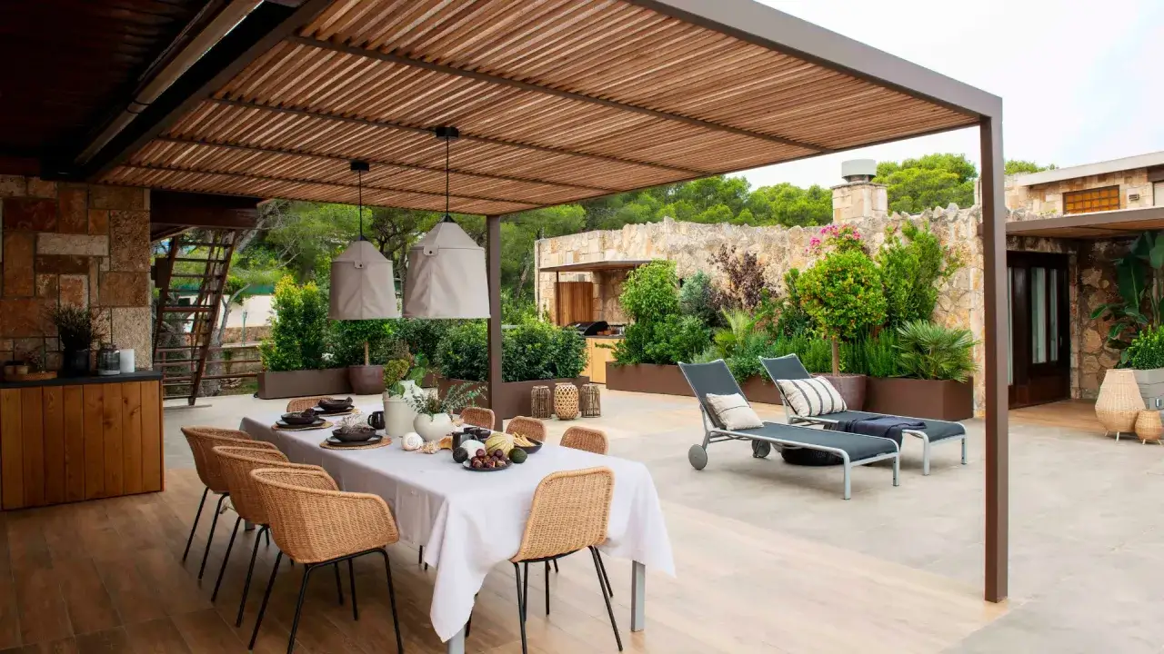 Elegantes terrazas acristaladas decoracion con mesa puesta, tumbonas y vegetaci&oacute;n exuberante.