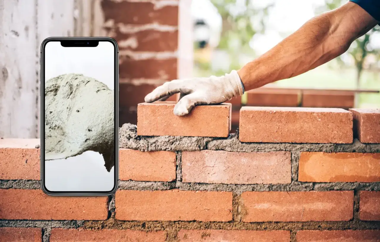 Un tel&eacute;fono muestra una pila de cemento, mientras una mano enguantada coloca un ladrillo sobre una pared en construcci&oacute;n. As&iacute; es que se usa el mortero.