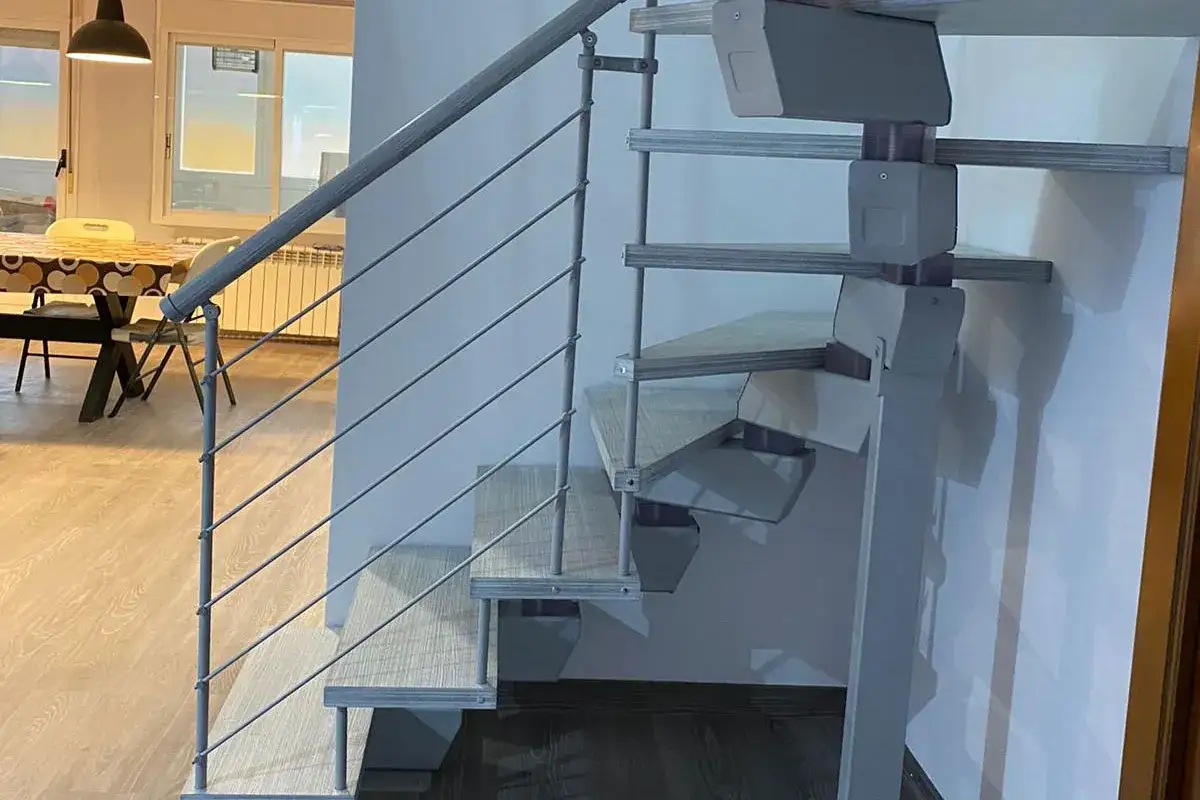 Escalera moderna con peldaños de madera y barandilla metálica. Varios tipos de escaleras se pueden apreciar en el diseño interior.