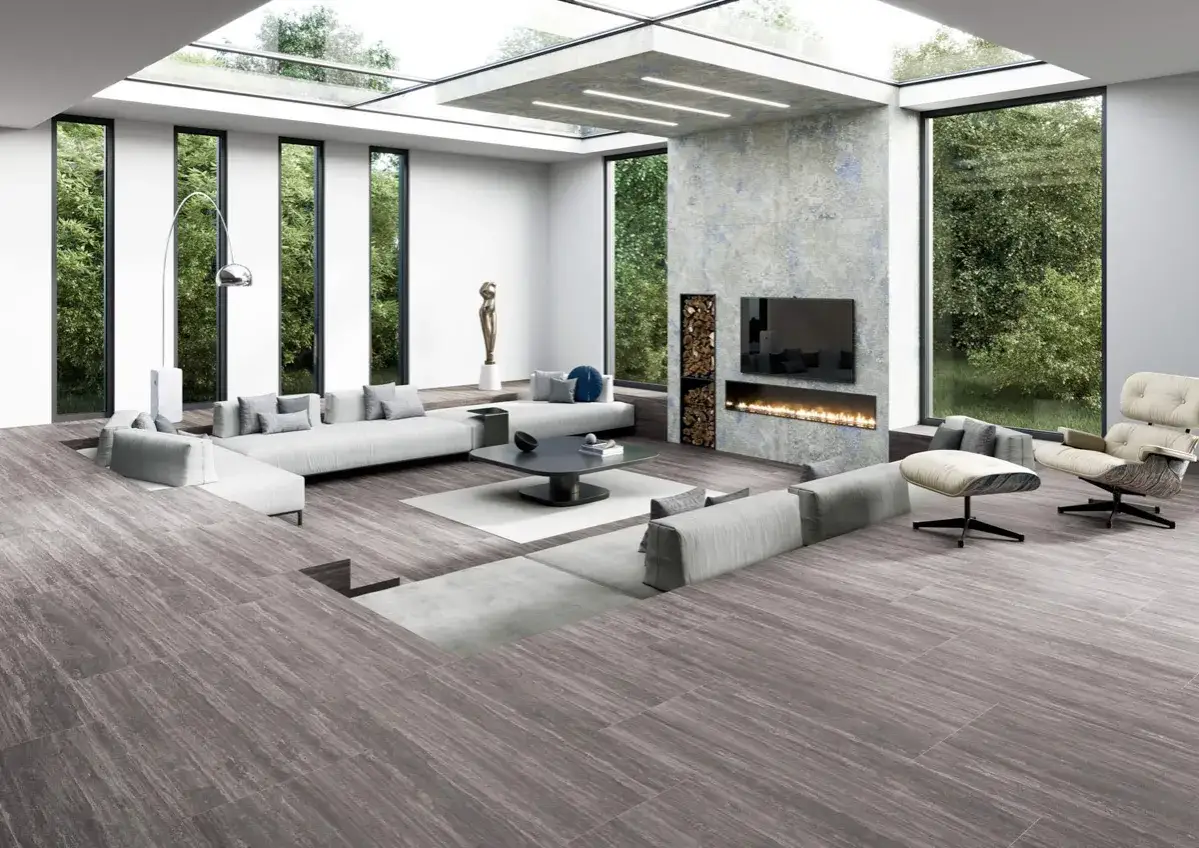 Elegante sal&oacute;n con chimenea, sof&aacute;s modulares y grandes ventanales. El suelo de madera, con distintos tipos de parquet, aporta calidez.