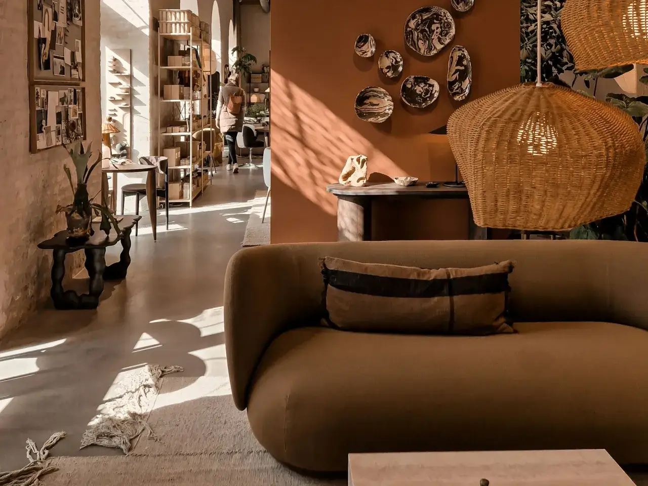 Sof&aacute; marr&oacute;n, l&aacute;mpara de mimbre y arte en la pared, ideas para decorar habitaci&oacute;n con estilo natural.