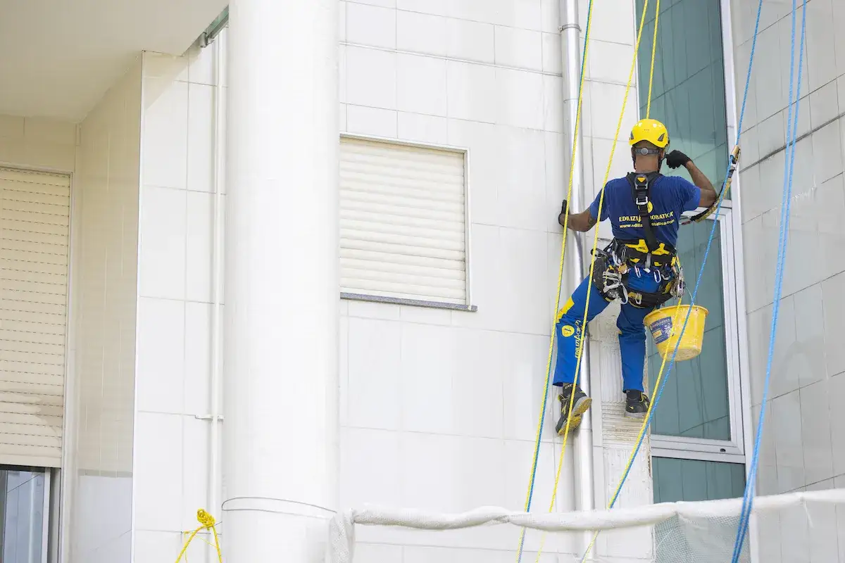 Trabajador en altura, con arnés y casco, realizando labores de mantenimiento. ¿Qué es el ITE? Es la inspección técnica de edificios.