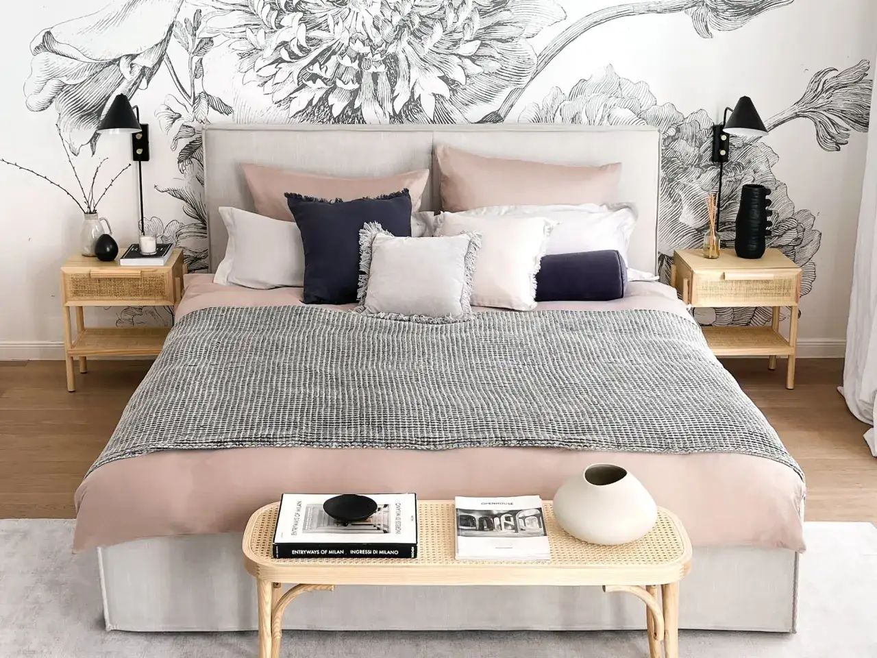 Habitaci&oacute;n con papel tapiz floral, cama con cojines y manta, mesitas de noche de rat&aacute;n. Unos pocos metros cuadrados de una habitaci&oacute;n normal, acogedora y elegante.